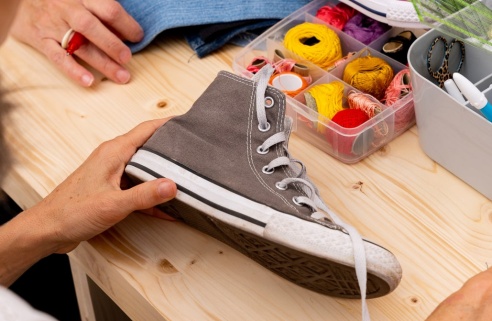 femme fait de la couture sur une chaussure en tissu