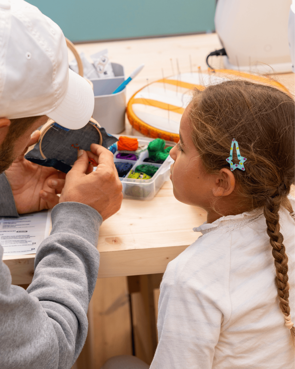 Un adulte apprend à un enfant à broder sur un tissu